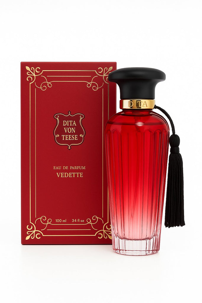 Produktfoto des Dita Von Teese Vedette Eau de Parfum 100 ml – luxuriöse rote Glasflasche mit schwarzem Verschluss und Quaste, vor eleganter roter Verpackung 